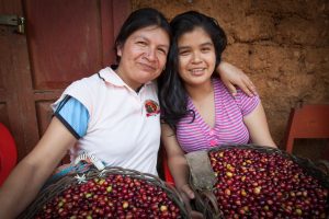 Coffee farmer and Cafe Femenino co-founder Erlita Baca Arce with her daughter, Ketty, holding baskets of red hand-picked coffee cherries